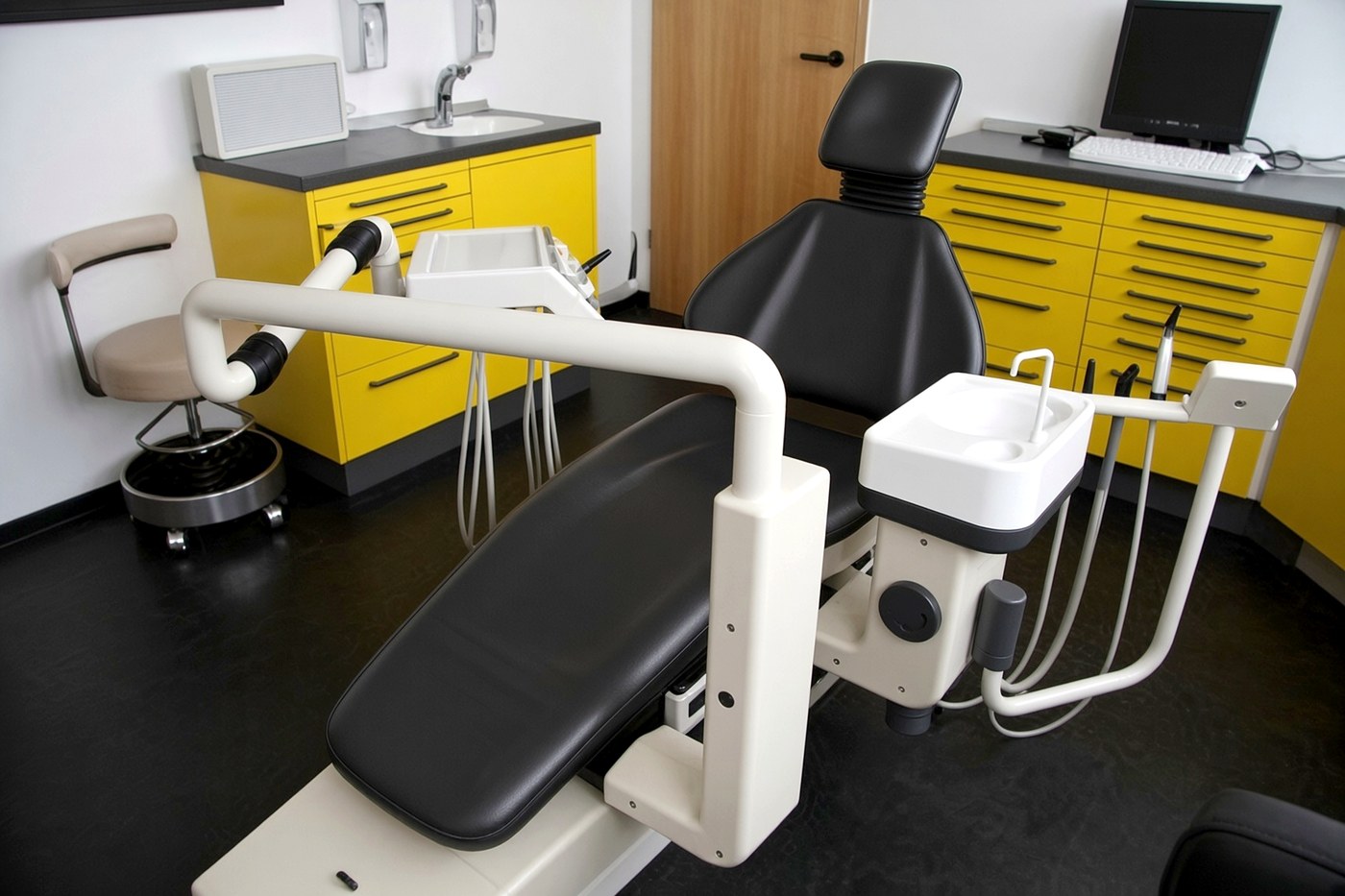 Behandlungszimmer mit gelben Schränken und schwarzem Stuhl