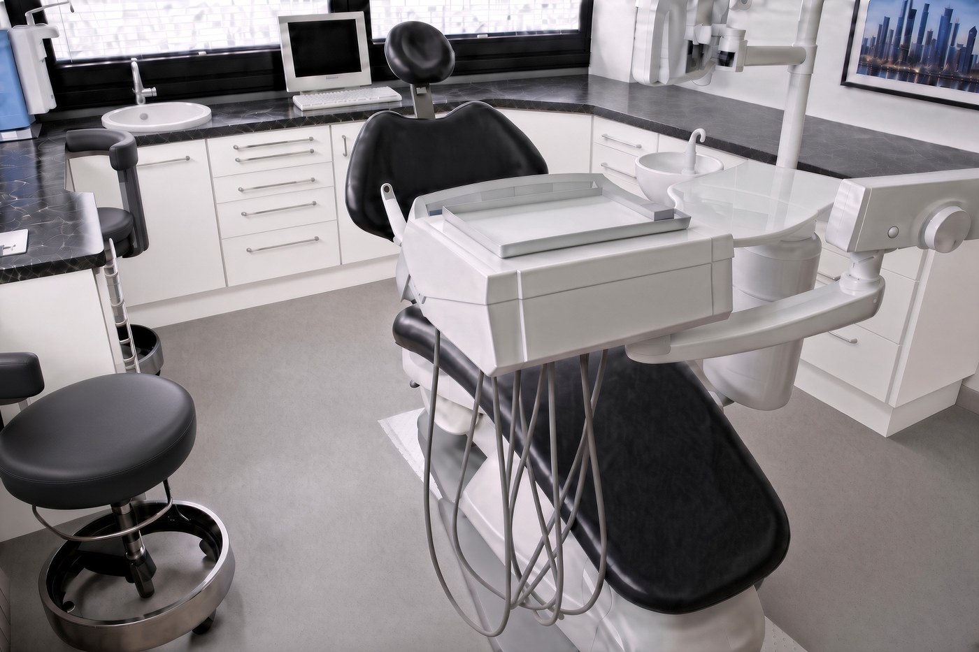 Behandlungszimmer mit weißen Schränken und schwarzem Stuhl